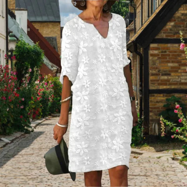 Weißes Damen A-Linien Kleid mit Blumenmuster, V-Ausschnitt. Aus zartem Stoff gefertigt, ideal für sommerliche Anlässe.