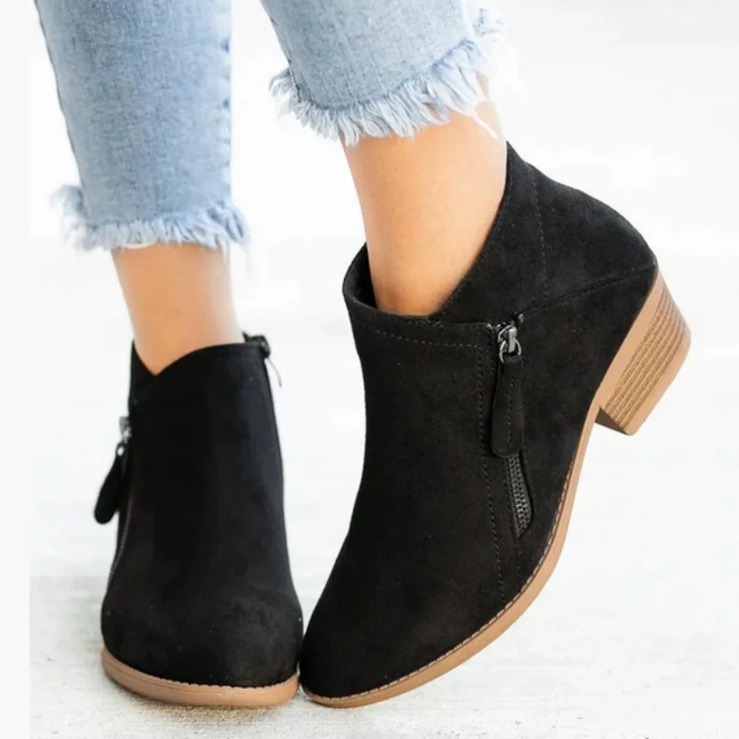 Schwarze Damen Ankelstiefel aus Kunstleder mit seitlichem Reißverschluss und flachem Profil für einfachen Ein- und Ausstieg.