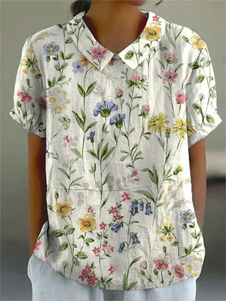 Weiße Damen Bluse mit floralem Stickmuster und kurzen Ärmeln, ideal für den Sommer und aus leichtem, atmungsaktivem Stoff.