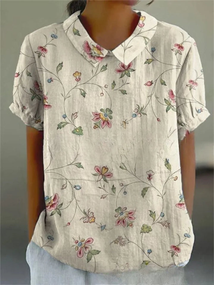 Weiße Damenbluse mit floralem Stickmuster, kurzen Ärmeln. Leichtes, luftiges Material für Frühling und Sommer.