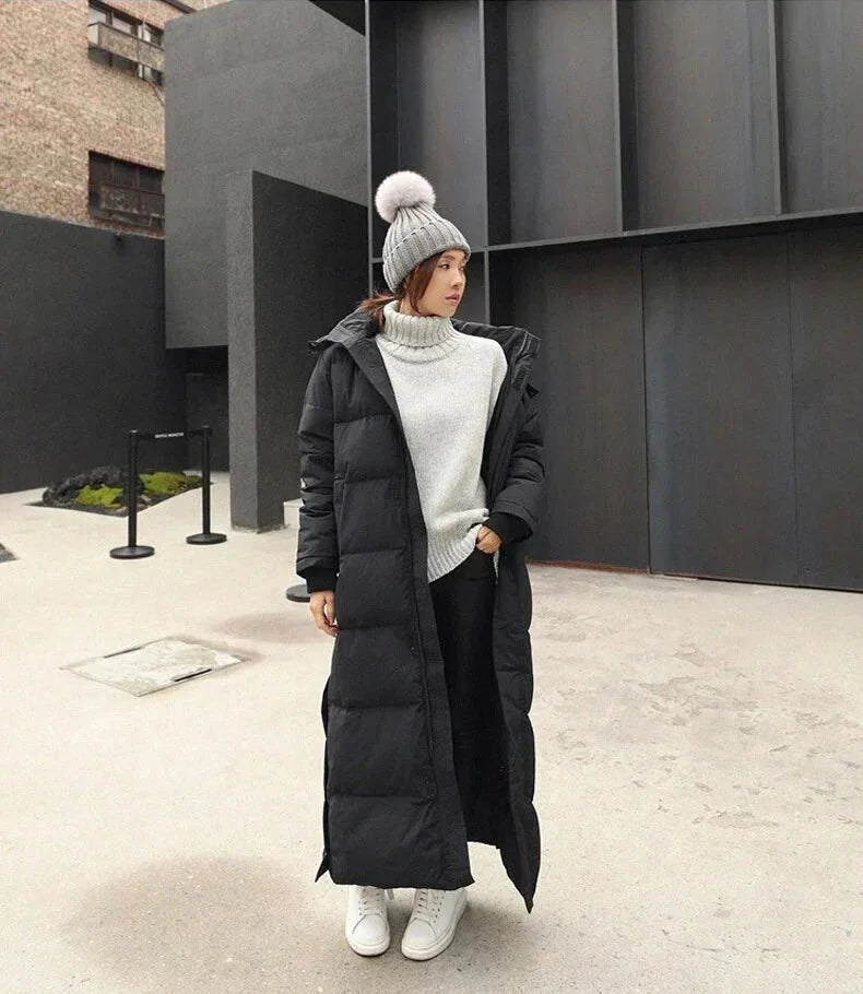 Schwarze Damen Lang Steppjacke aus strapazierfähigem Material mit Kapuze und praktischen Seitentaschen.