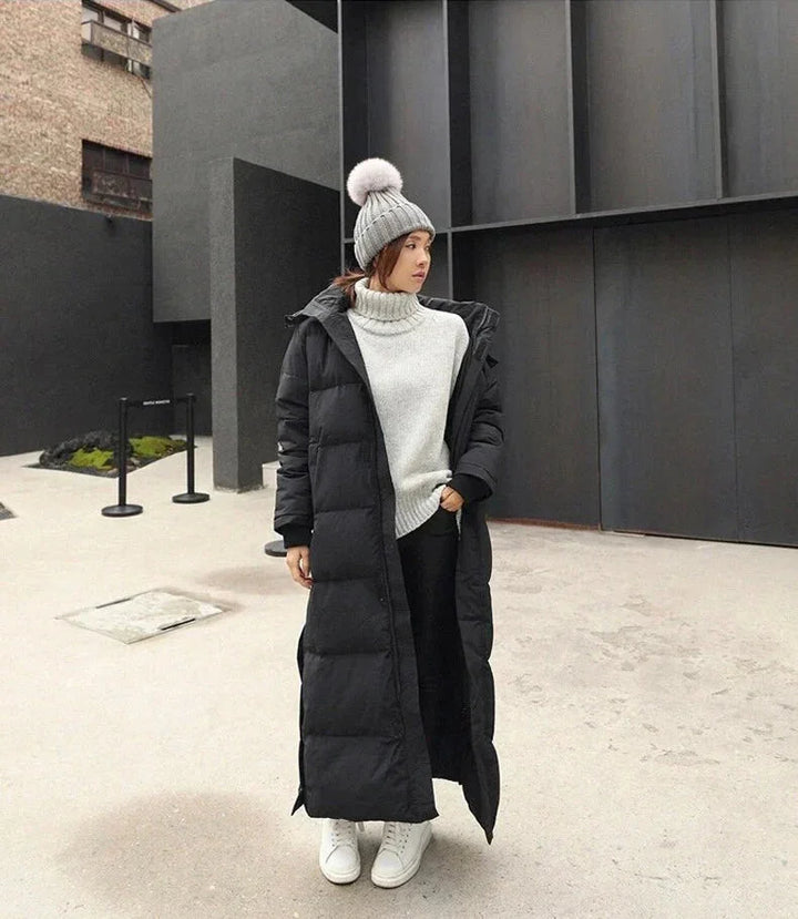 Schwarze Damen Lang Steppjacke aus strapazierfähigem Material mit Kapuze und praktischen Seitentaschen.