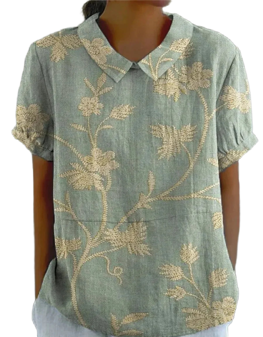 Grüne Damenbluse mit kurzem Ärmel und Stickdetails, aus leichtem Stoff, verziert mit floralem Muster.