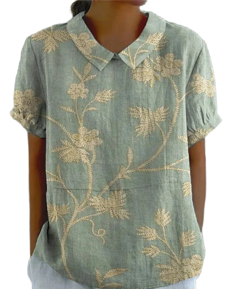 Grüne Damenbluse mit kurzem Ärmel und Stickdetails, aus leichtem Stoff, verziert mit floralem Muster.