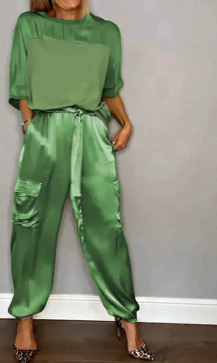 Damen Jumpsuit aus satinisiertem Material in Grün, mit praktischen Taschen und einem bindbaren Gürtel für eine taillierte…