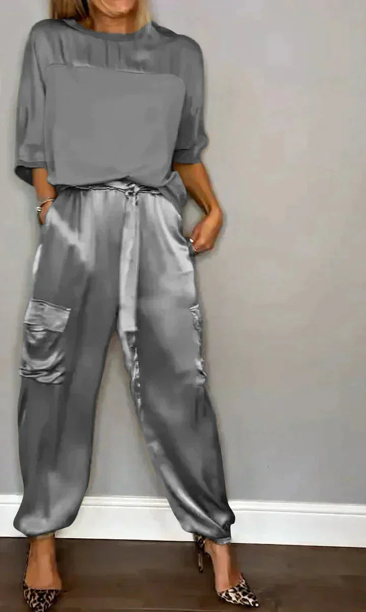 Damen Satin Jumpsuit in Grau mit Taschen, Bindegürtel und elegantem Schnitt für einen bequemen, stilvollen Look.