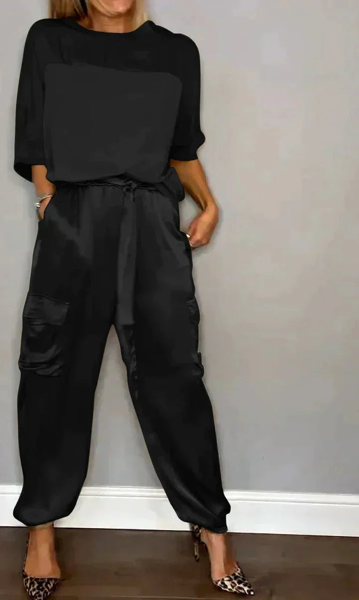 Schwarzer Damen Satin Jumpsuit mit Taschen, Bindegürtel und schmalem Schnitt für einen eleganten Look.