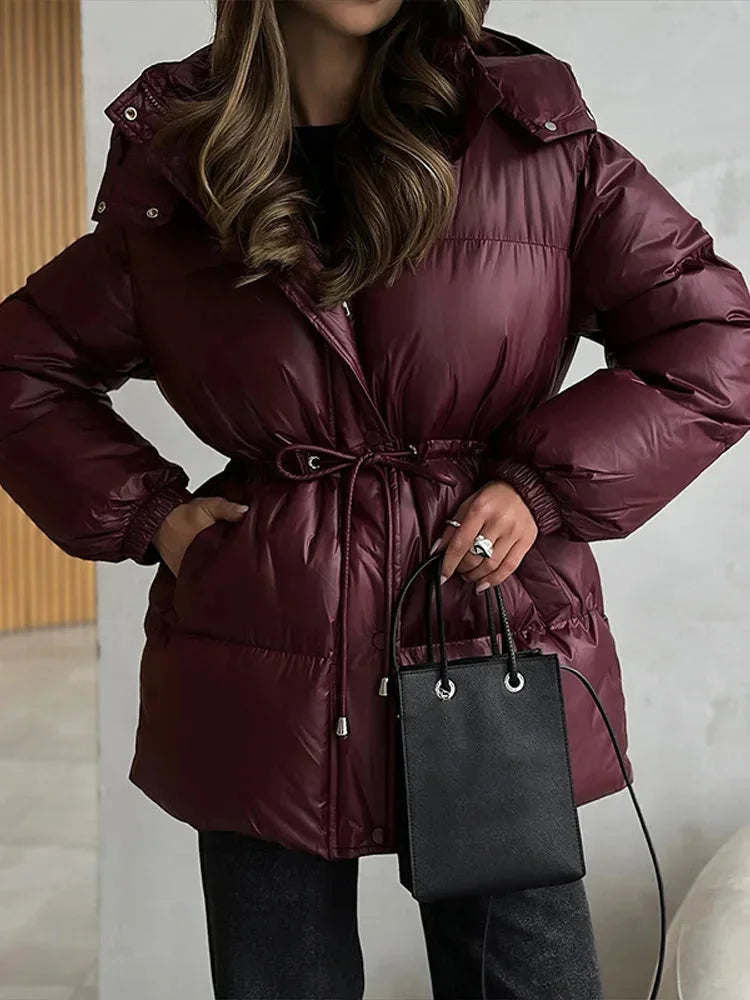 Damen Steppjacke mit Taillenzug und Kapuze aus leichtem, wärmeisolierendem Material für den Winter 2025.