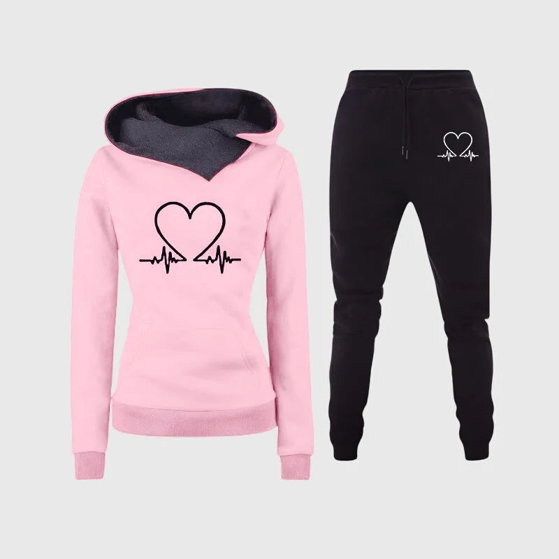Damen Trainingsset in Rosa mit Herzmotiv, Kapuzenpullover und bequemer Passform aus atmungsaktivem Material.
