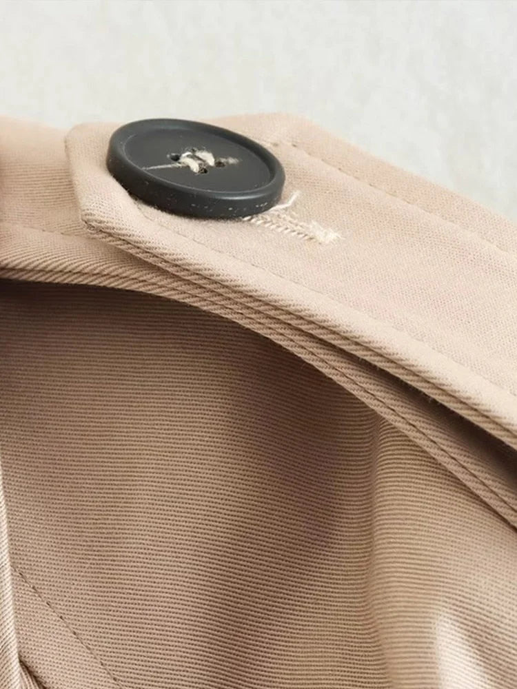 Beiger Damen Trenchcoat, kurz geschnitten, taillenbetont, aus leichter Baumwolle, mit klaren Linien und klassischen Knöpfen.