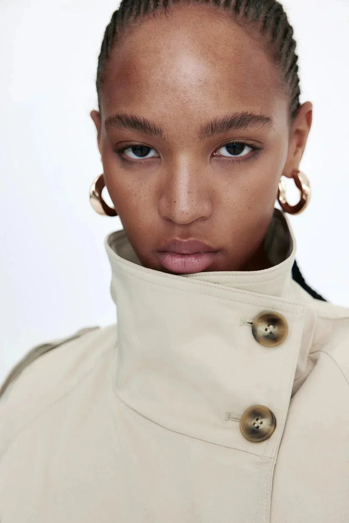 Damen Trenchcoat mit hohem Kragen und Taillengürtel aus robustem Stoff in klassischem Schnitt, ideal für Übergangszeiten.