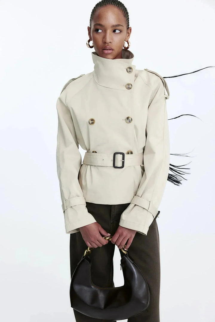 Beiger Damen Trenchcoat aus leichtem Material, mit hohem Kragen und taillierbarem Gürtel für eine individuelle Passform.