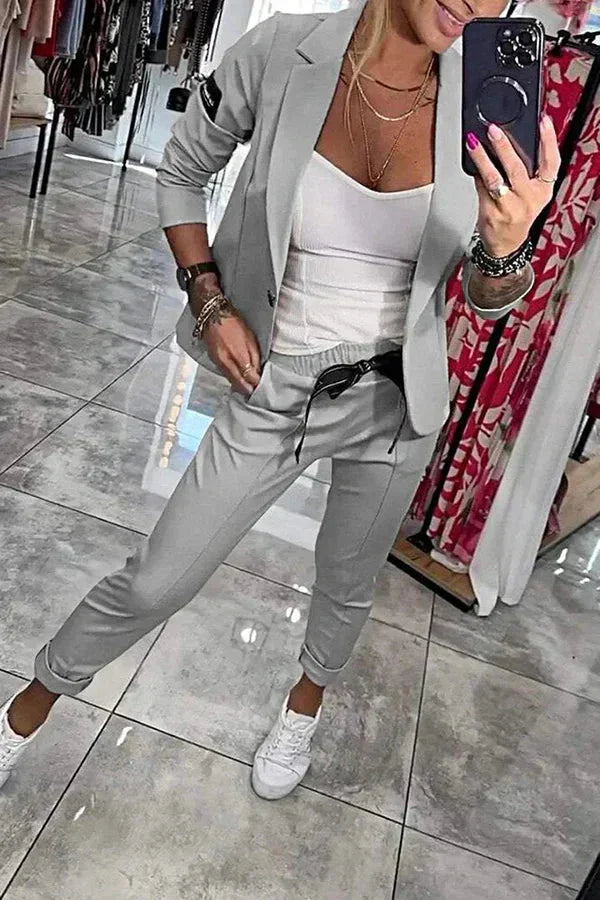 Grauer Damenanzug mit Joggerhose und Blazer, aus softem Material, lässiger Schnitt für den Alltag, bequem und modisch.
