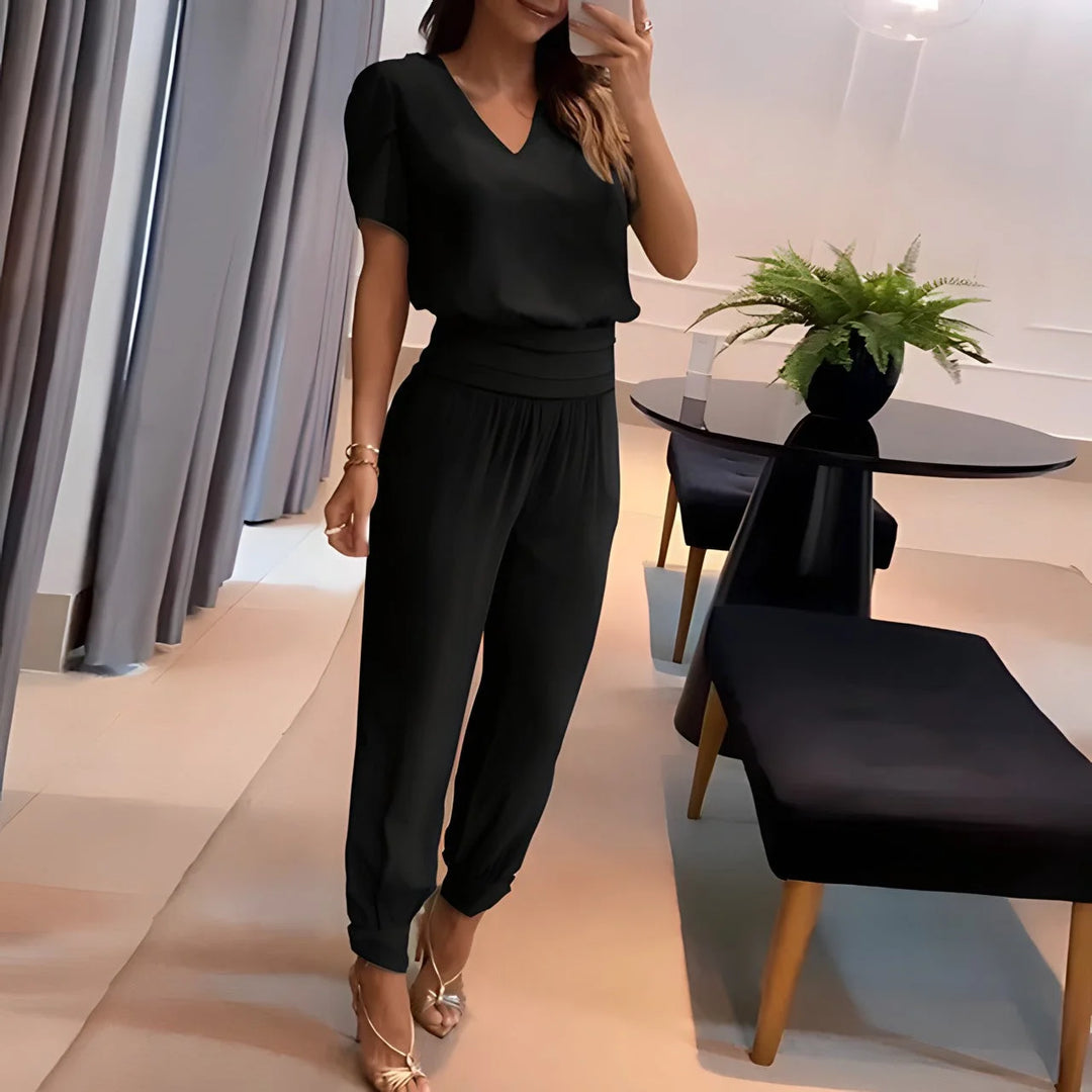 Schwarze Damenbluse aus leichtem Baumwollmix, kombiniert mit gemusterter Hose für einen stilvollen Look.