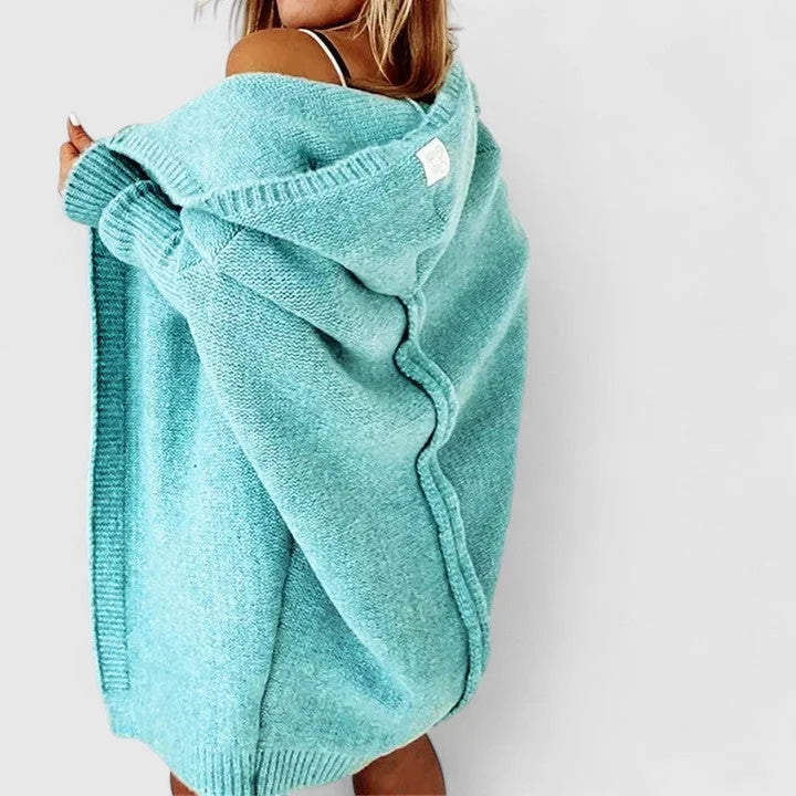 Oversized Damen Strickjacke mit Kapuze aus weichem, warmem Material, mit aufgesetzten Taschen und lässigem Schnitt.